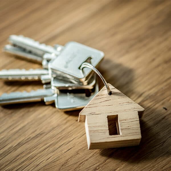 Das Bild zeigt einen Schlüsselbund mit einem Haus-Holzanhänger