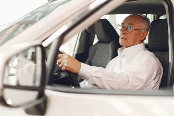 Das Foto zeigt einen älteren Mann beim Autofahren.