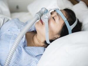 Eine schlafende Frau trägt eine CPAP-Maske.
