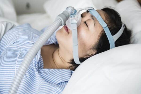Eine schlafende Frau trägt eine CPAP-Maske.