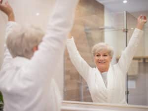 Das bild zeigt eine ältere Frau vor einem Spiegel.
