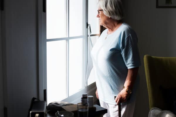Das Bild zeigt eine ältere Frau an einem Fenster.
