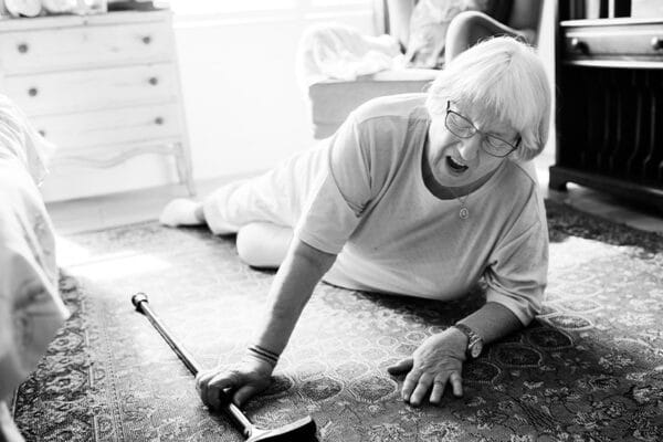 Das Bild zeigt eine ältere Frau, welche mit einem Laufstock gestürzt ist.