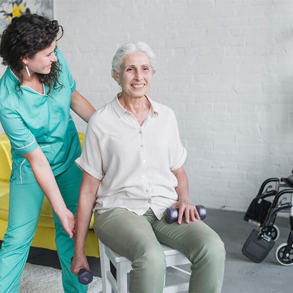 Das Bild zeigt eine Pflegerin, welche Ergotherapie-Übungen mit einer älteren Frau macht.