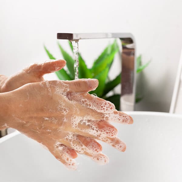 Das Bild zeigt die Hände, welche unter einem Wasserhahn gewaschen werden.